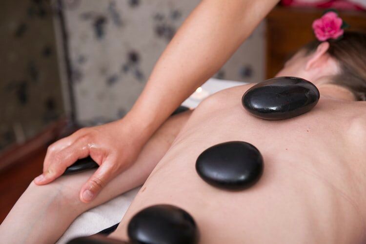 A woman is getting a massage with hot rocks on her back.