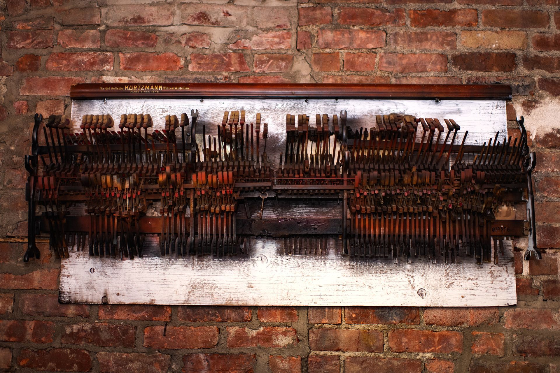 A large piece of art is hanging on a brick wall