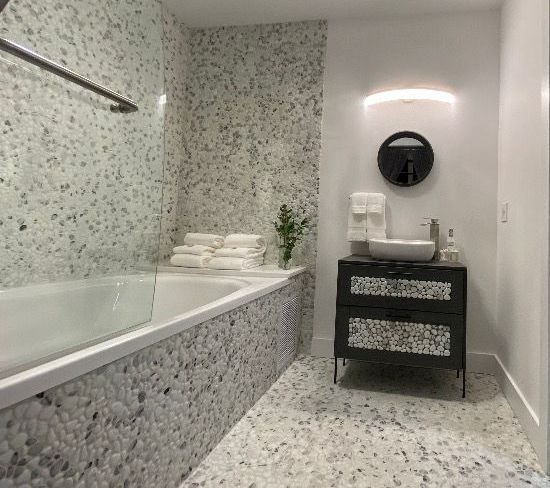 A bathroom with a bathtub , sink , mirror and towels.