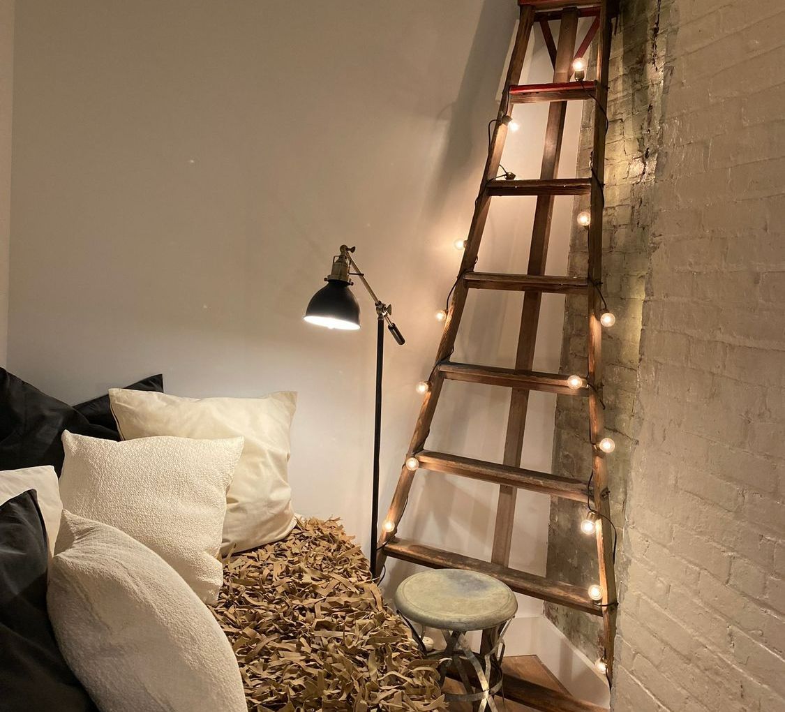A bedroom with a ladder and a lamp on the wall