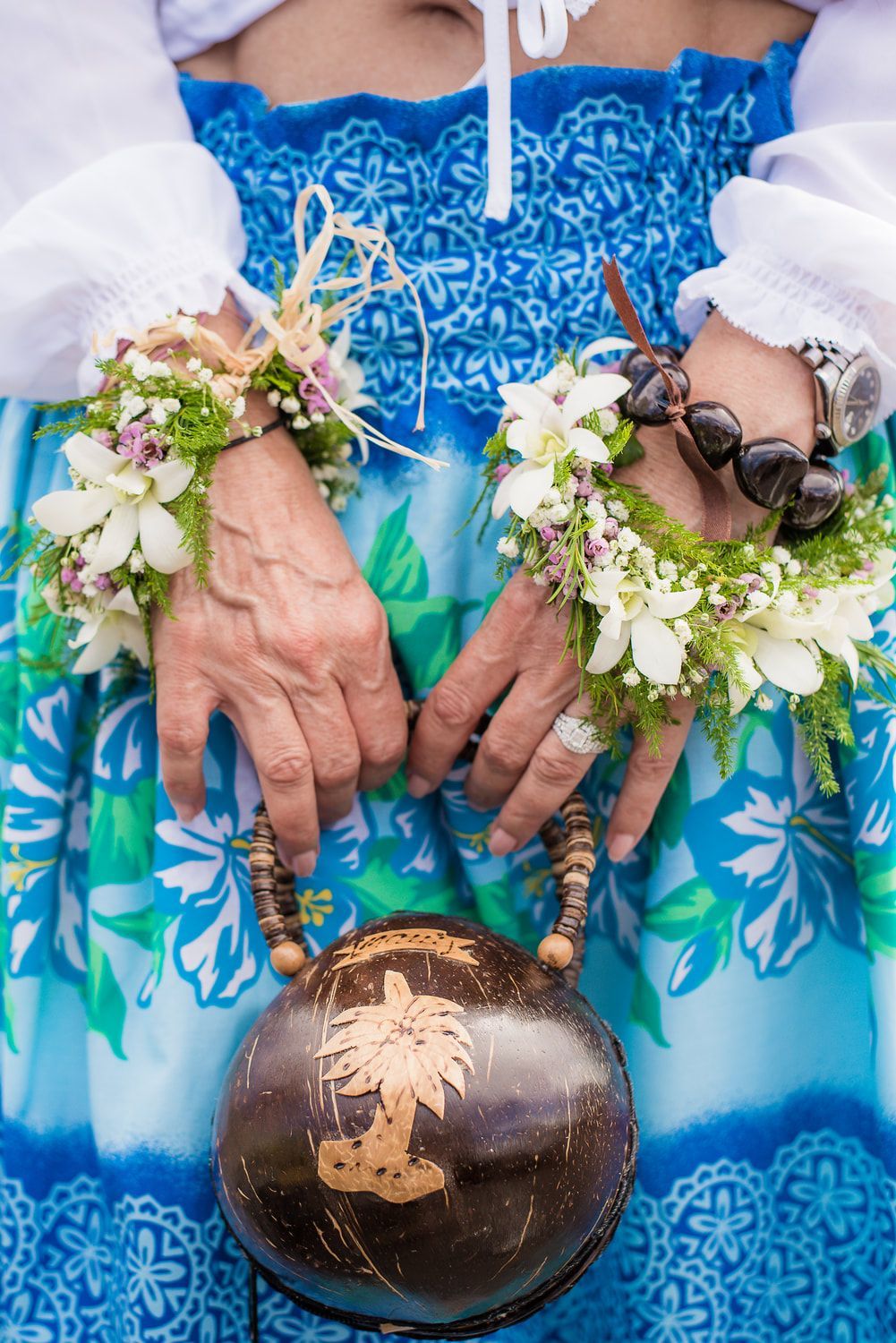 Wedding ceremony on the beach, officiant with couple, leis, ocean background.