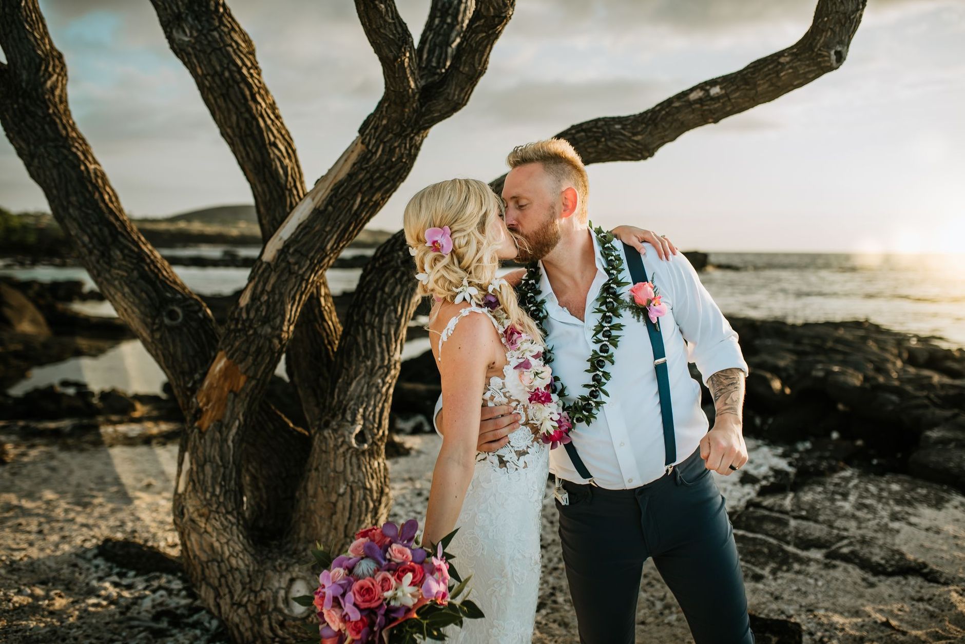 Newlyweds kiss as guests at a beach wedding on the Big Island of Hawaii. Simple Kona Beach Weddings.