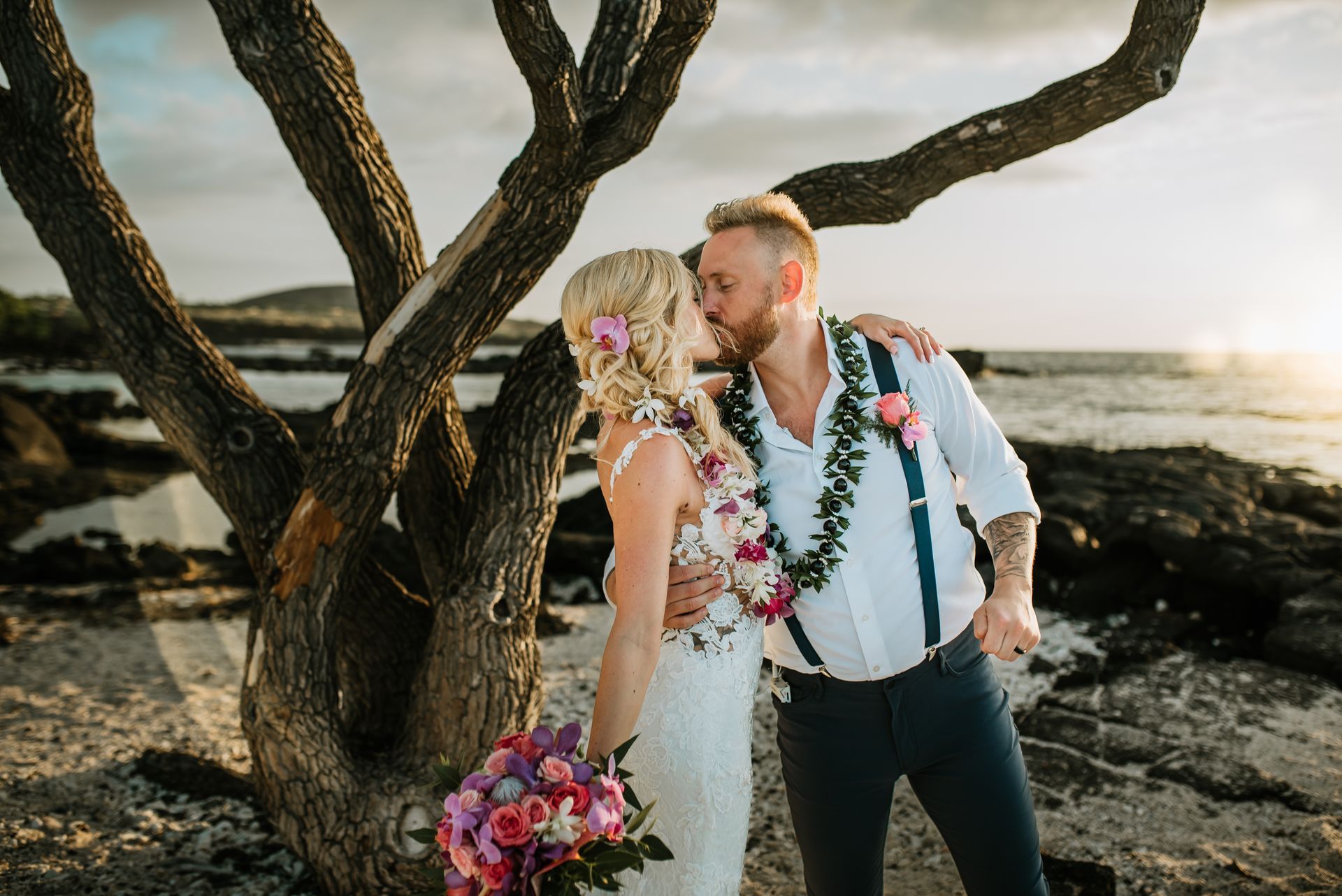 Newlyweds kiss as guests toss flower petals at beach wedding. Simple Kona Beach Weddings.