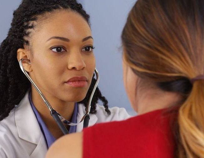 A doctor is listening to a patient 's heartbeat with a stethoscope.