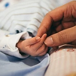 A close up of a person holding a baby 's hand.