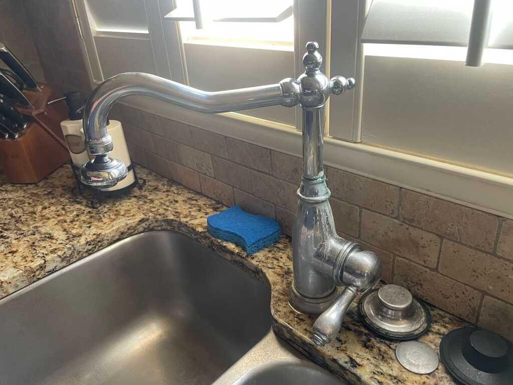 A kitchen sink with a faucet and a sponge on the counter.