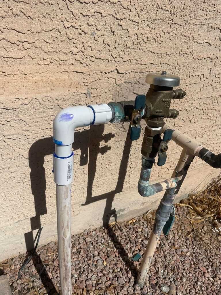 A hose with a valve attached to it is sitting next to a wall.