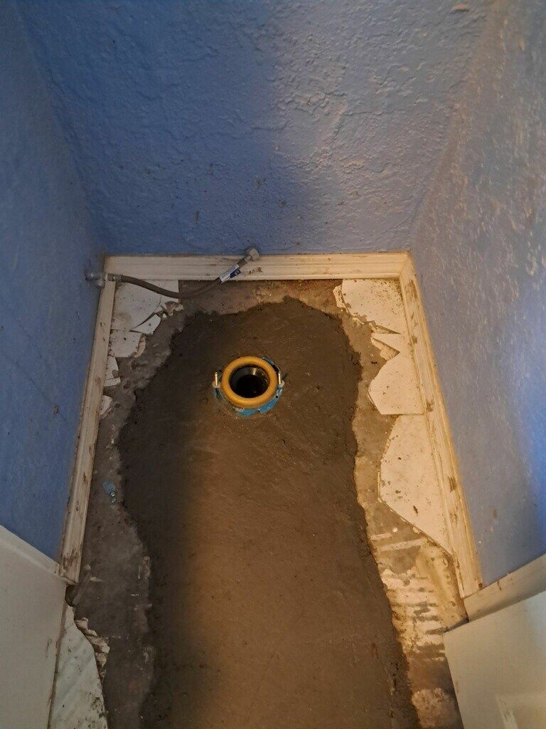 A toilet is being remodeled in a bathroom with a hole in the floor.