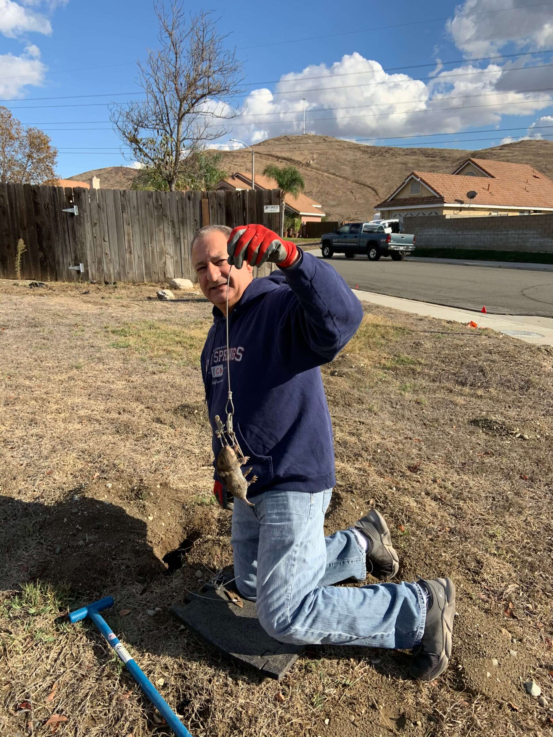 a man is kneeling down in the dirt with a shovel .