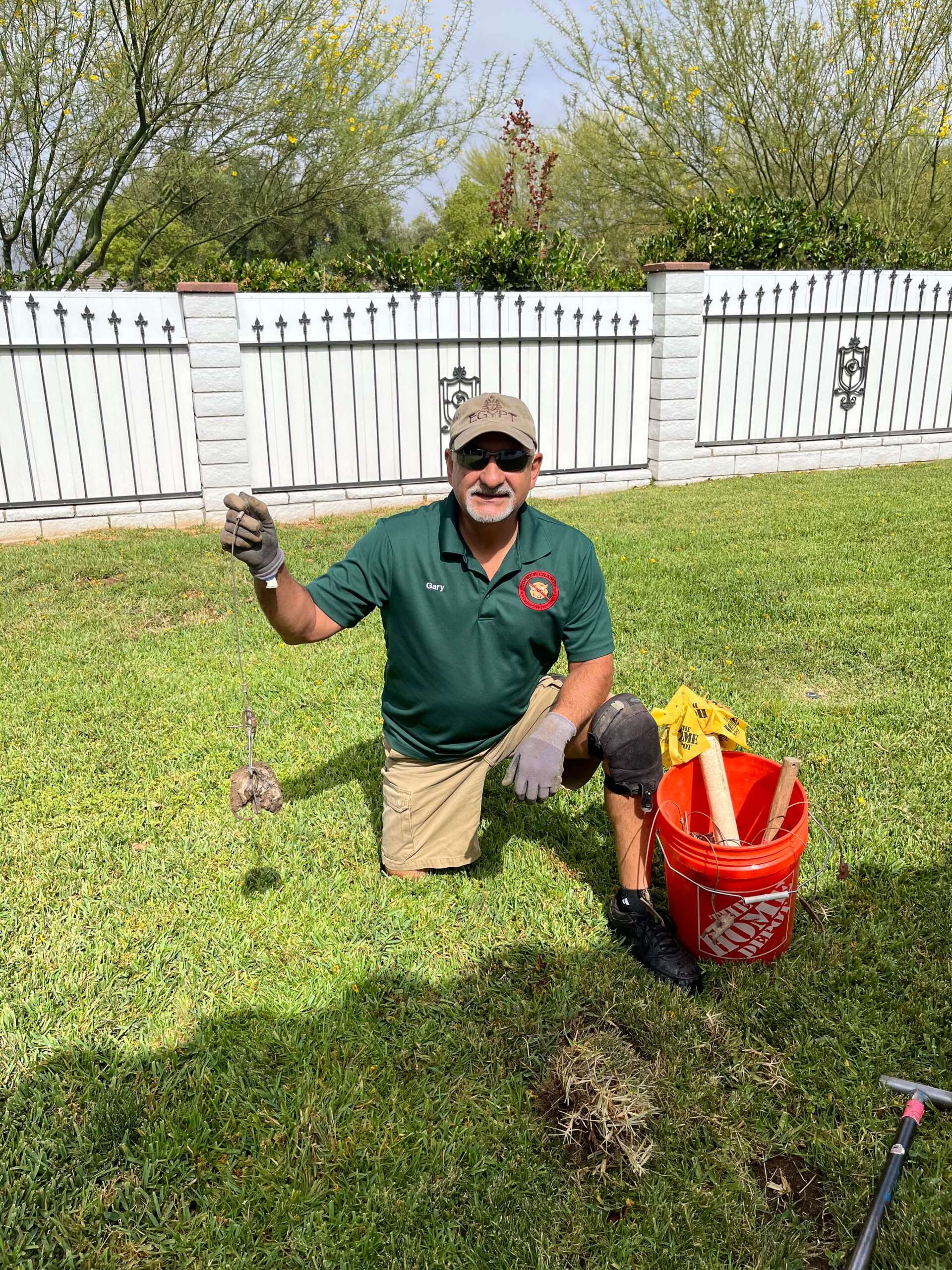 a man is kneeling in the grass with a shovel and bucket .