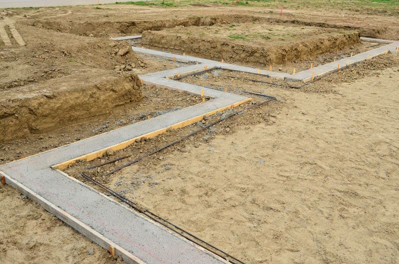 A concrete foundation is being built on a dirt field.