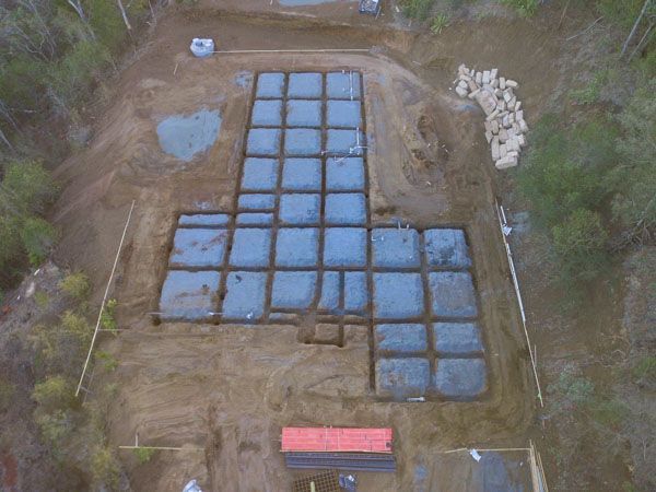 An aerial view of a building under construction in the middle of a forest.