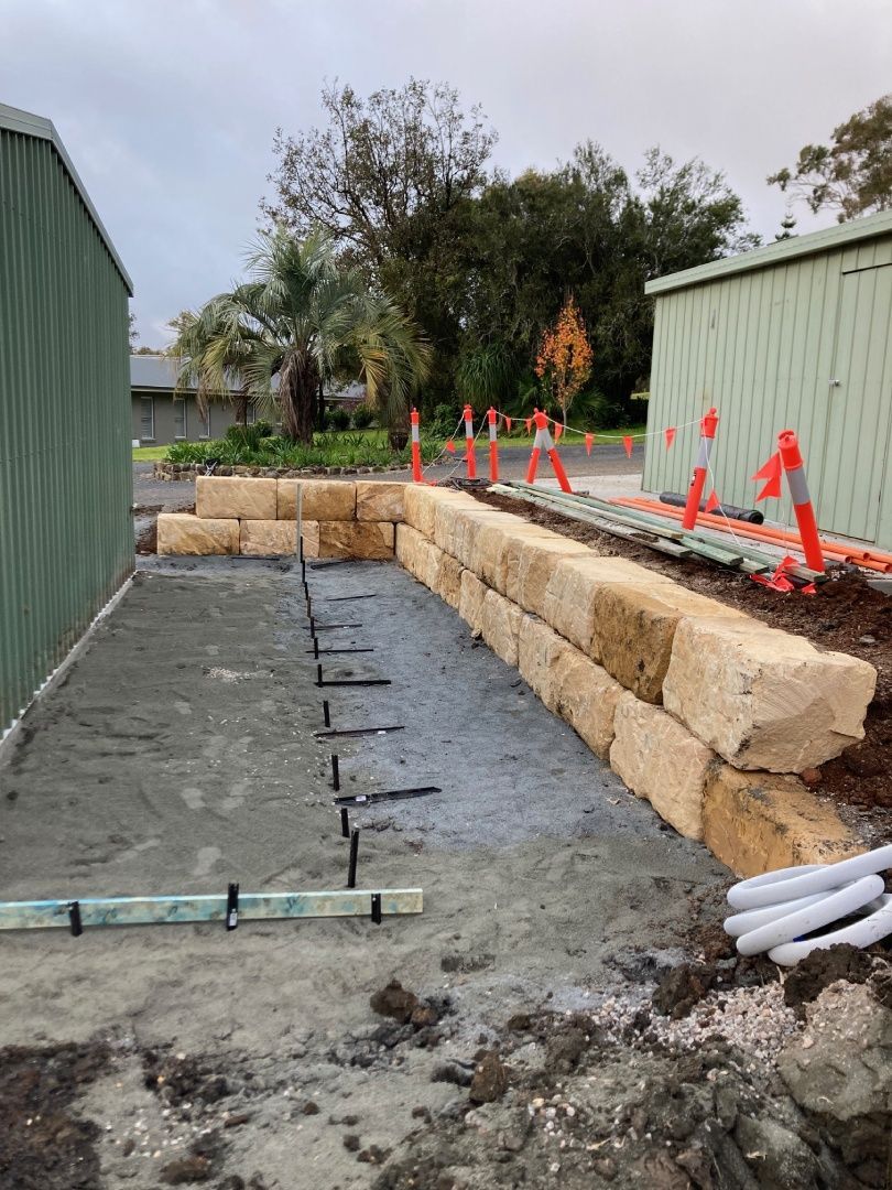 A stone wall is being built next to a fence.
