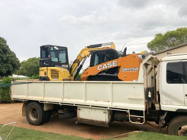 A case excavator is sitting on the back of a truck.