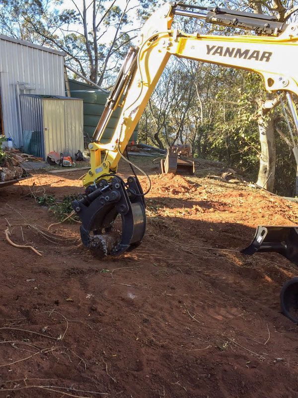 A yellow yanmar excavator is sitting on top of a dirt field.