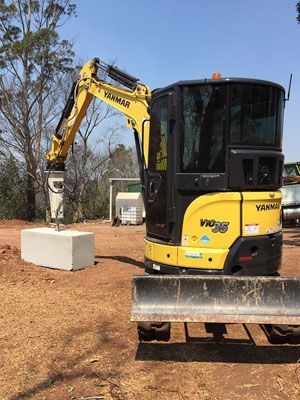 A yellow and black excavator is parked in a dirt field.