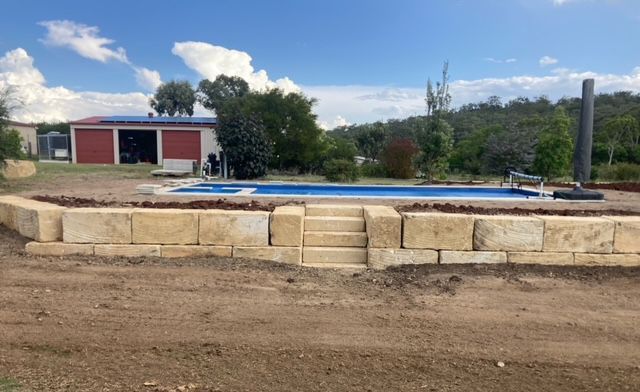 A large swimming pool is being built in the backyard of a house.
