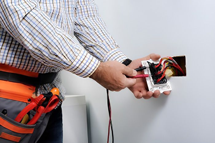 An Electrician Is Installing A Light Switch On A Wall — GJT Electrical In Warners Bay, NSW