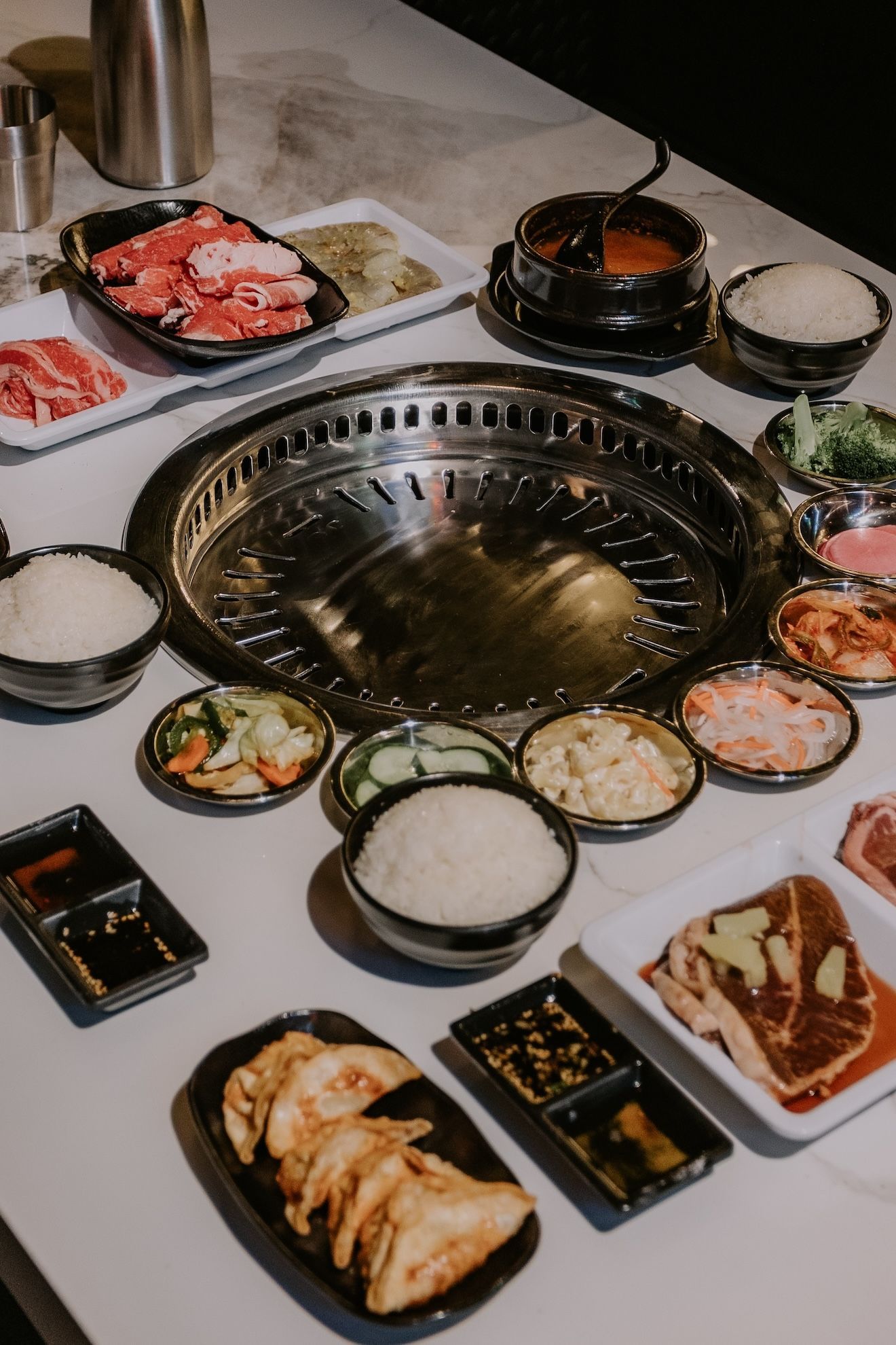 a table topped with plates of food and a grill .