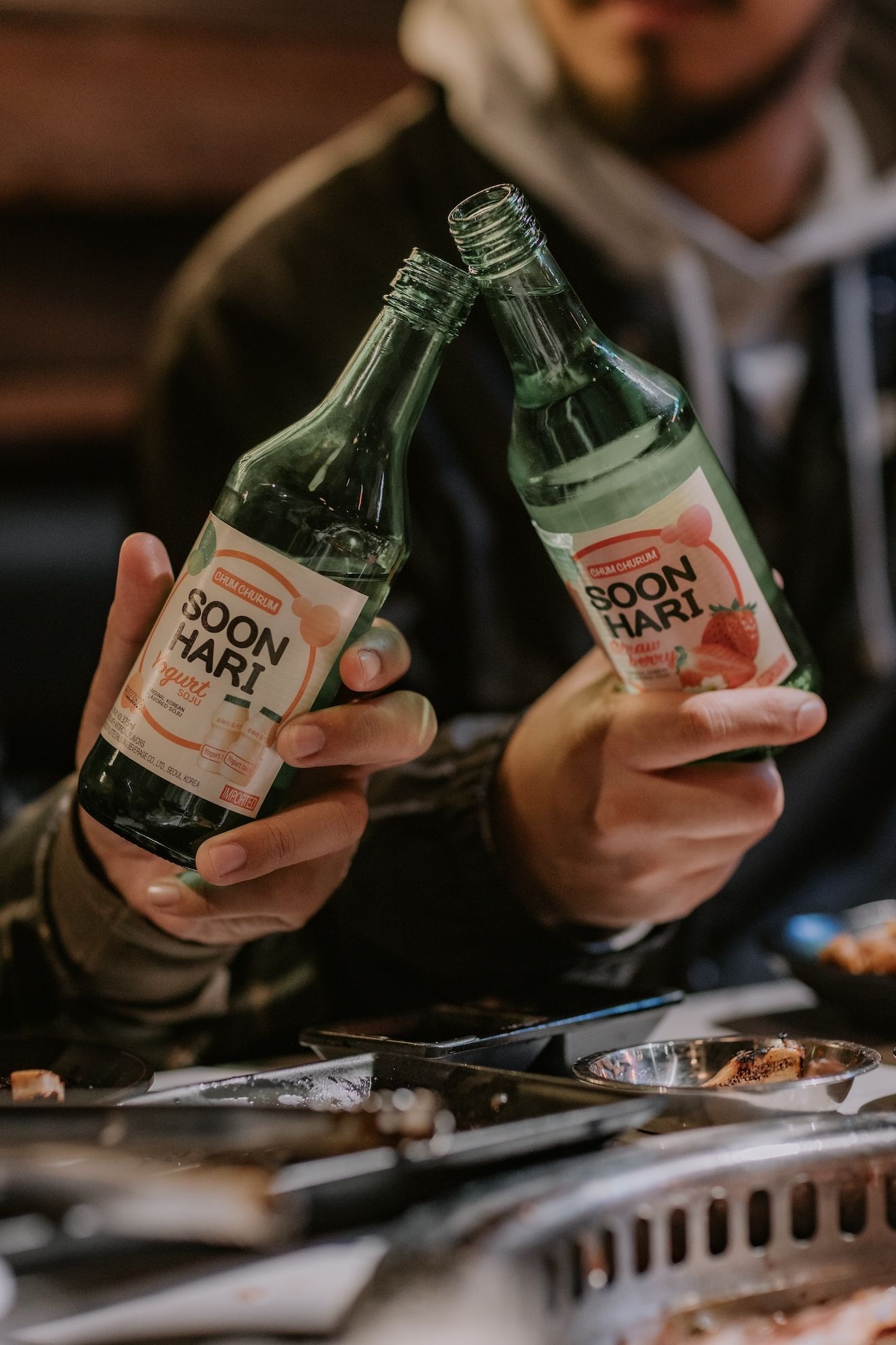a man is holding two bottles of soju in his hands .