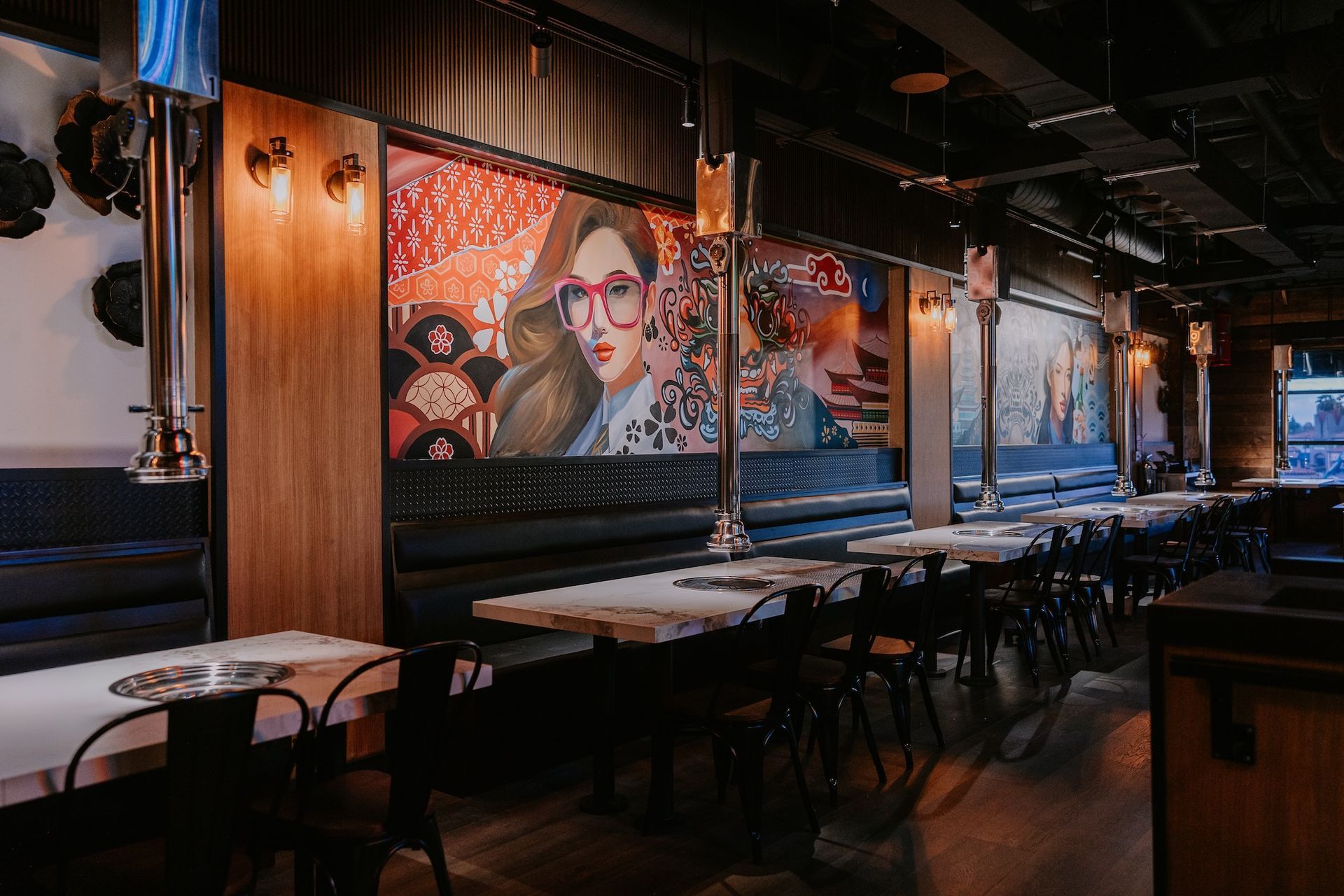 a restaurant with tables and chairs and a mural on the wall .