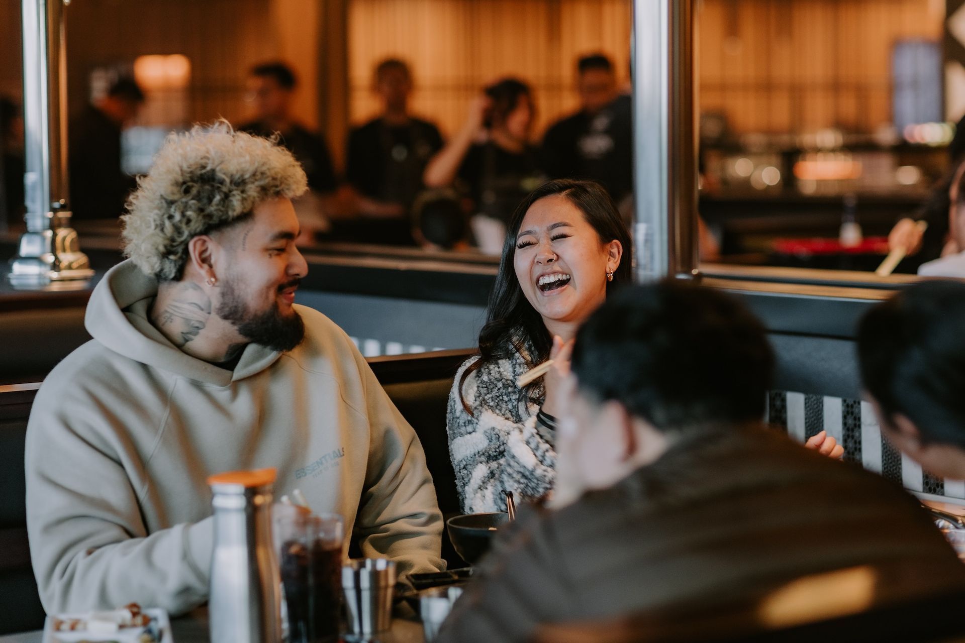 a group of people are sitting at a table in a restaurant laughing .