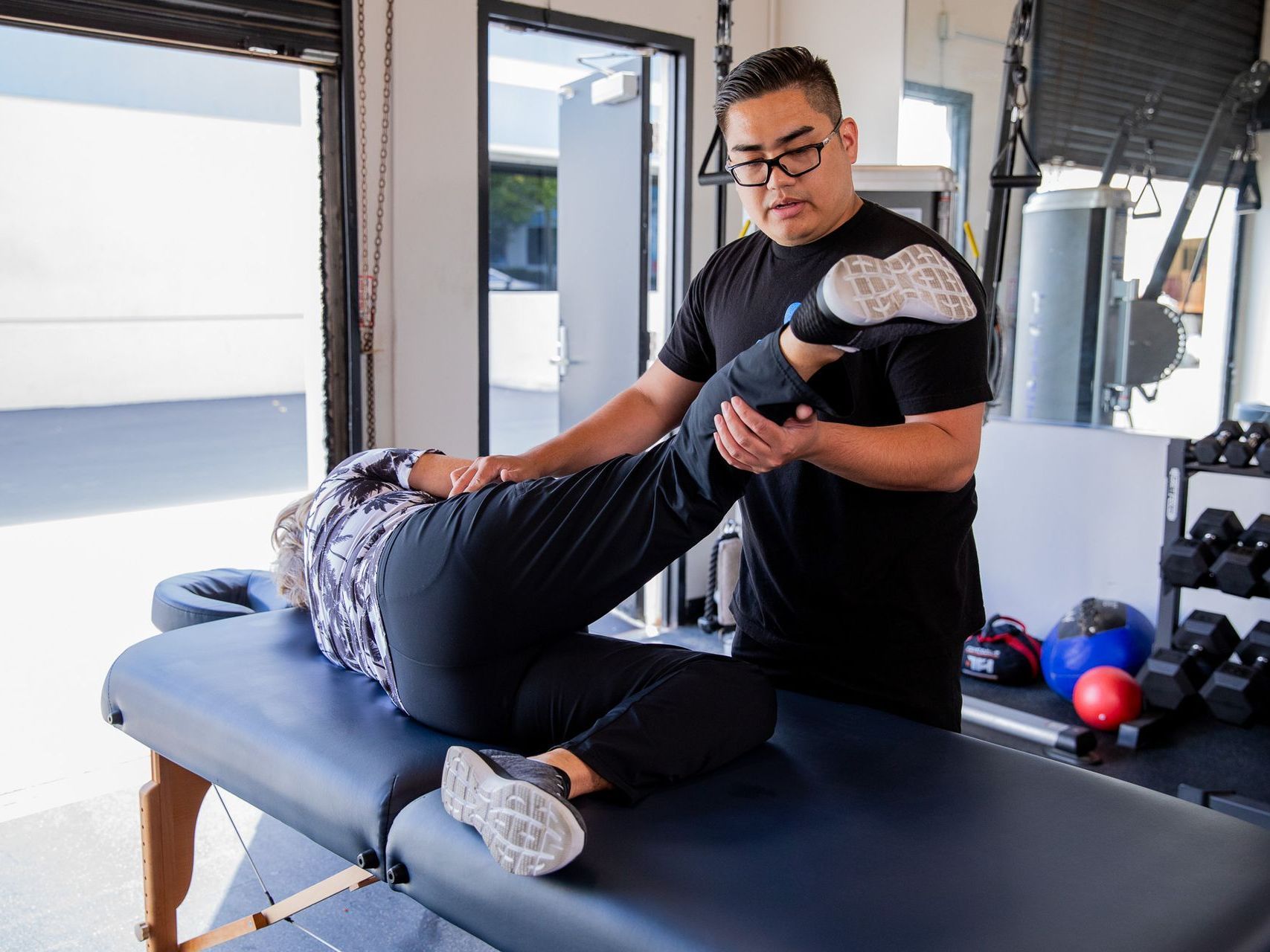 A man is stretching a woman 's leg on a table.
