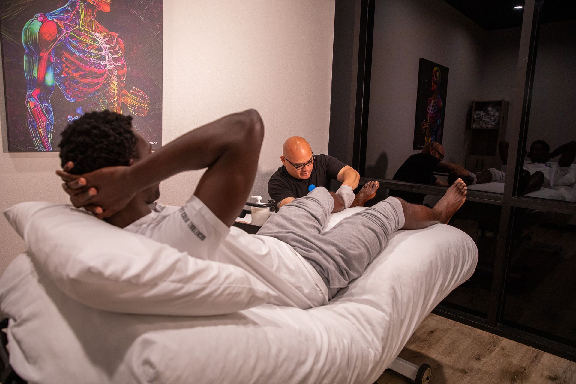 A man is laying on a bed while a doctor examines his leg.