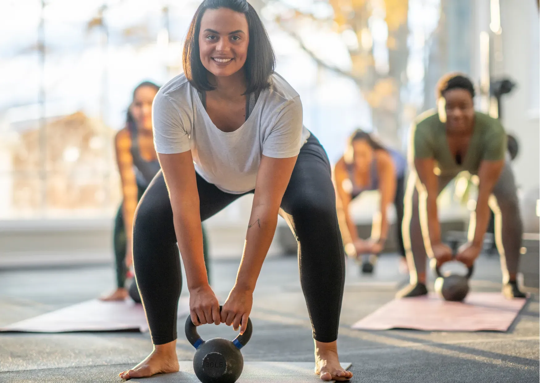 A woman is lifting a kettlebell in a gym.