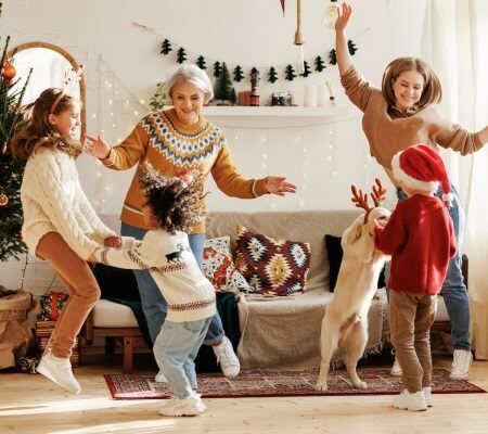 A group of people are dancing in a living room with a dog.