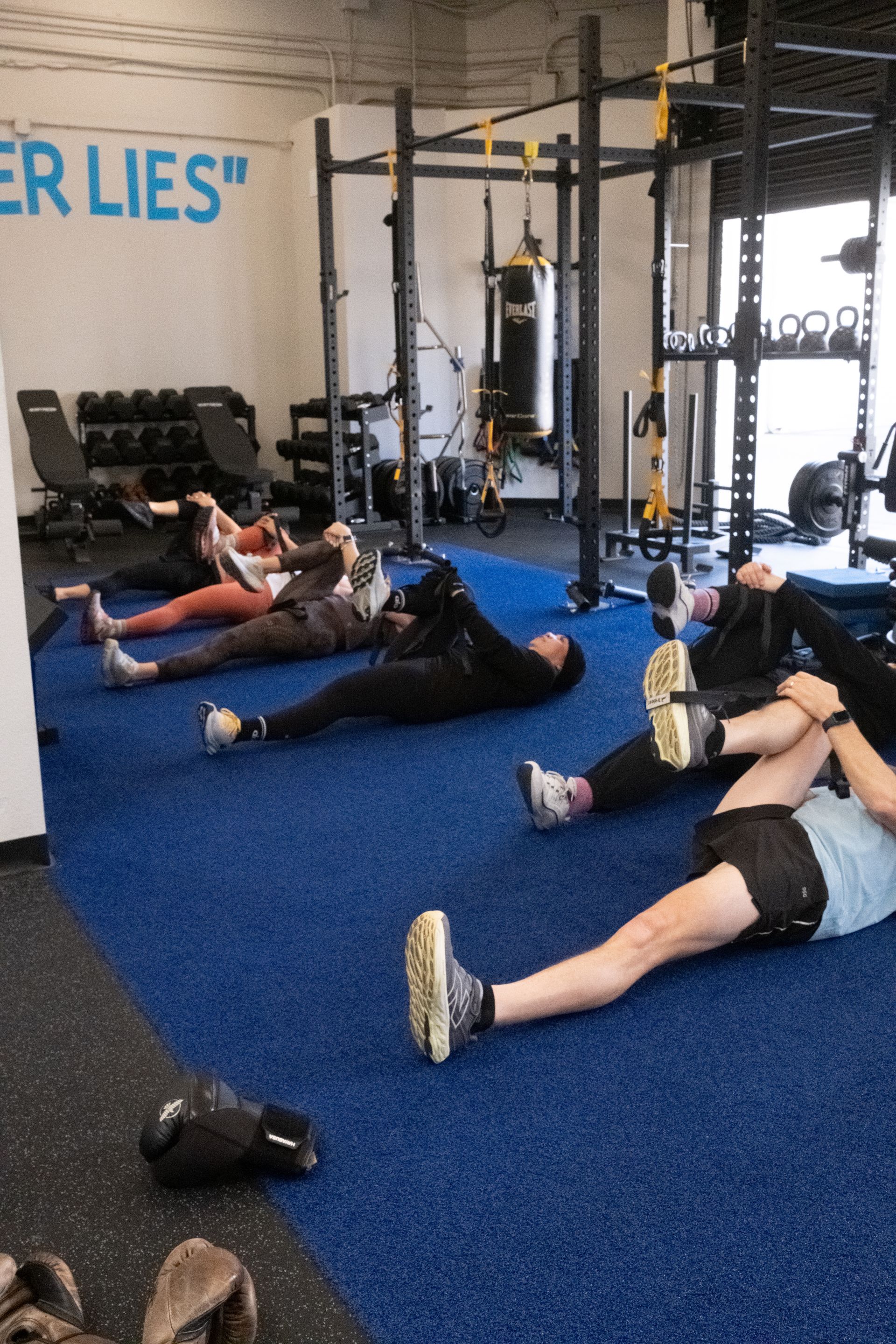 A group of people are laying on the floor in a gym.