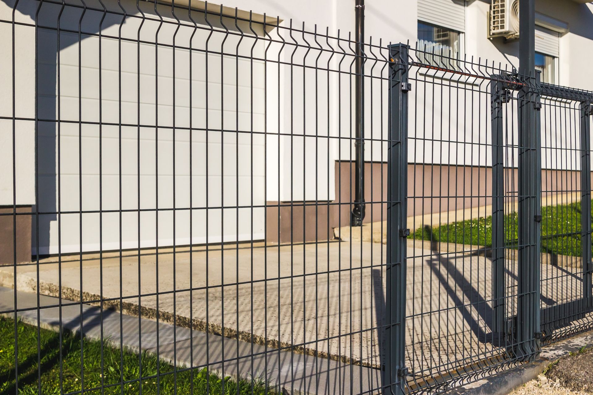 Black metal fence with gate in front of a house and stone walkway