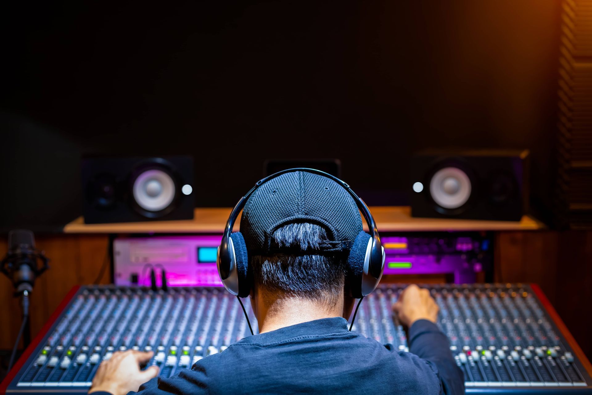 Person wearing headphones, mixing audio on a console in a recording studio.