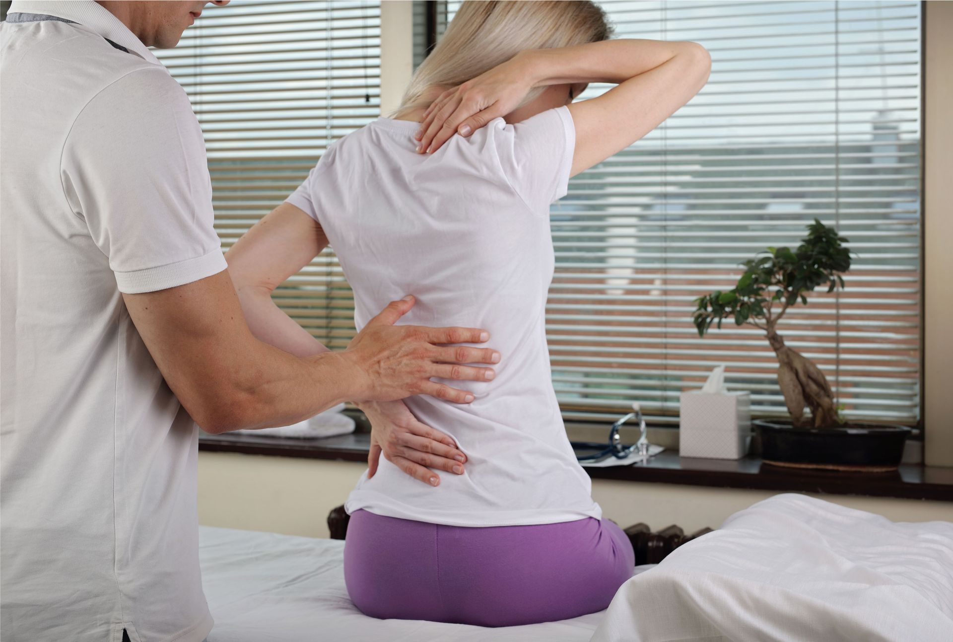 A woman is sitting on a table getting a massage from a man.