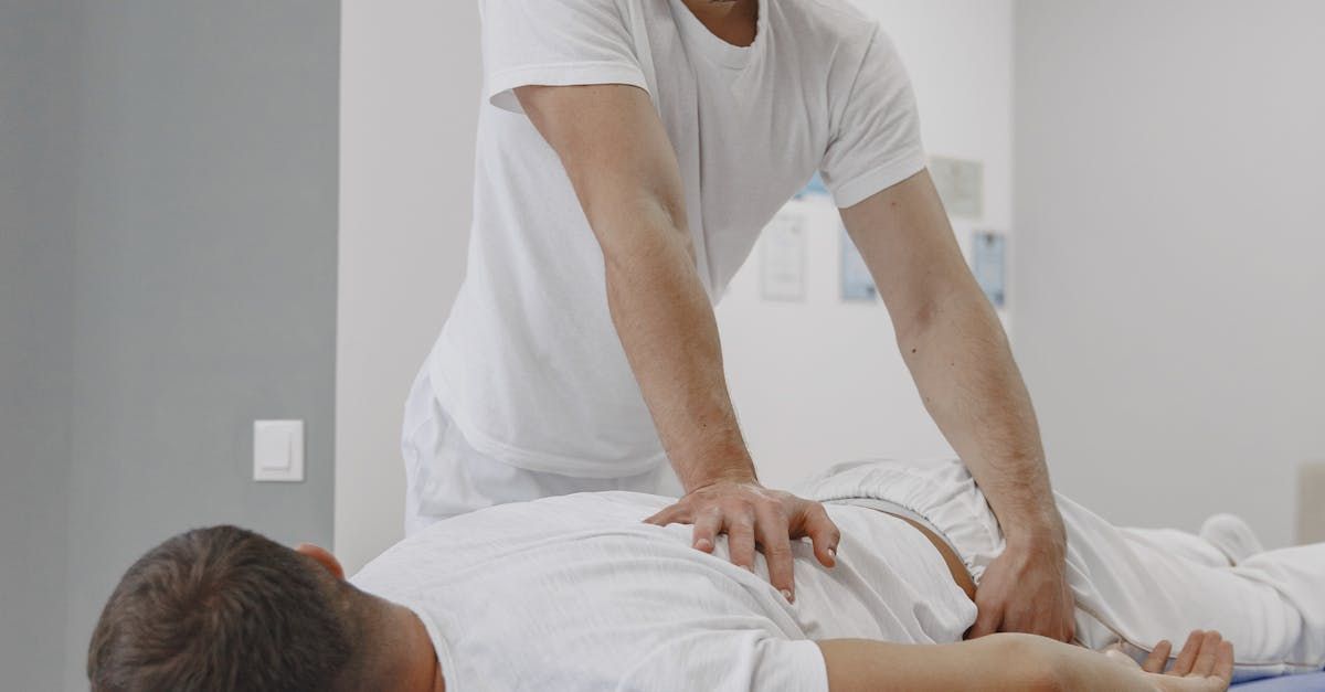 A man is laying on a bed getting a massage from a massage therapist.