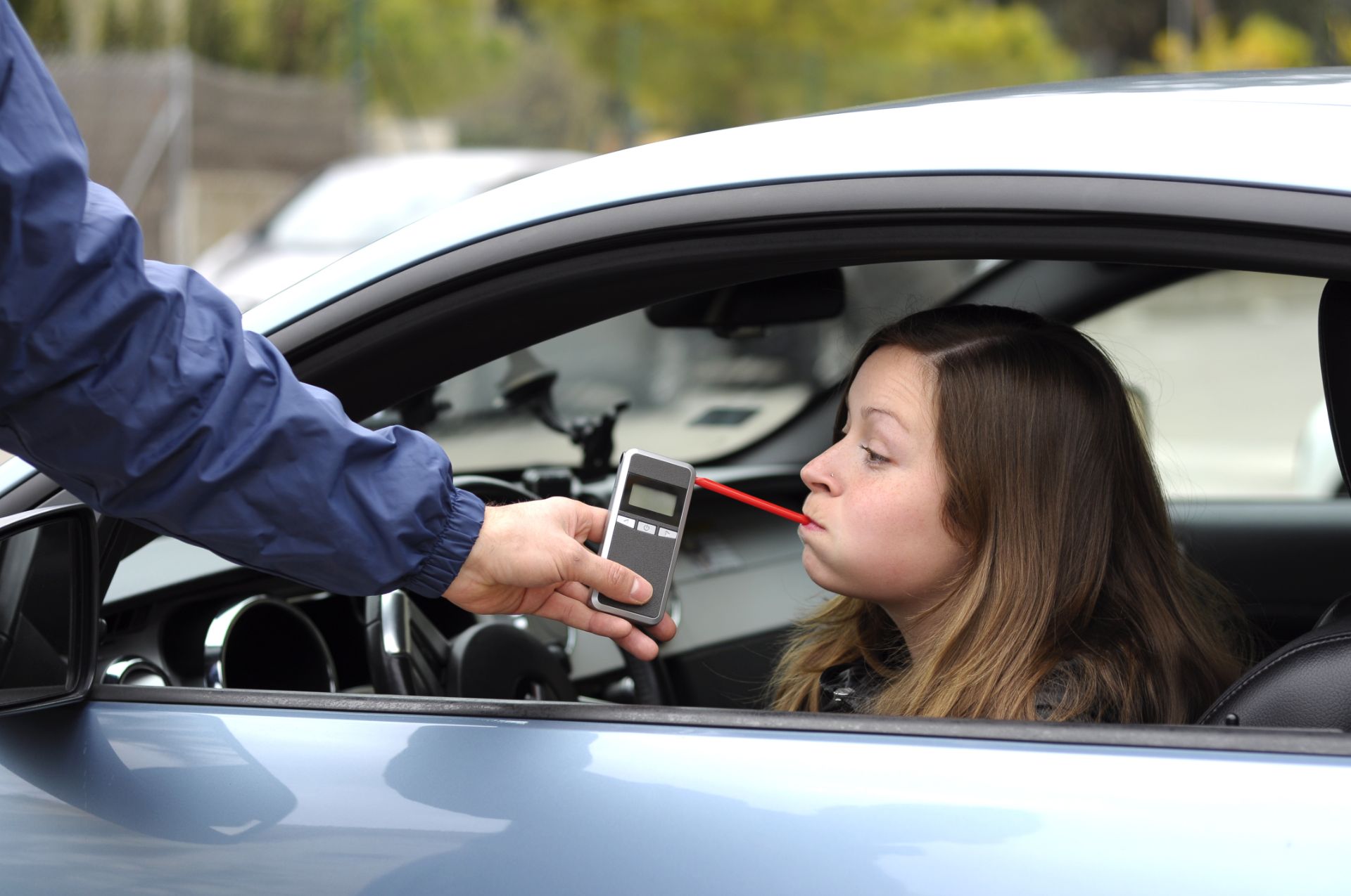 Woman in car taking breathalyzer