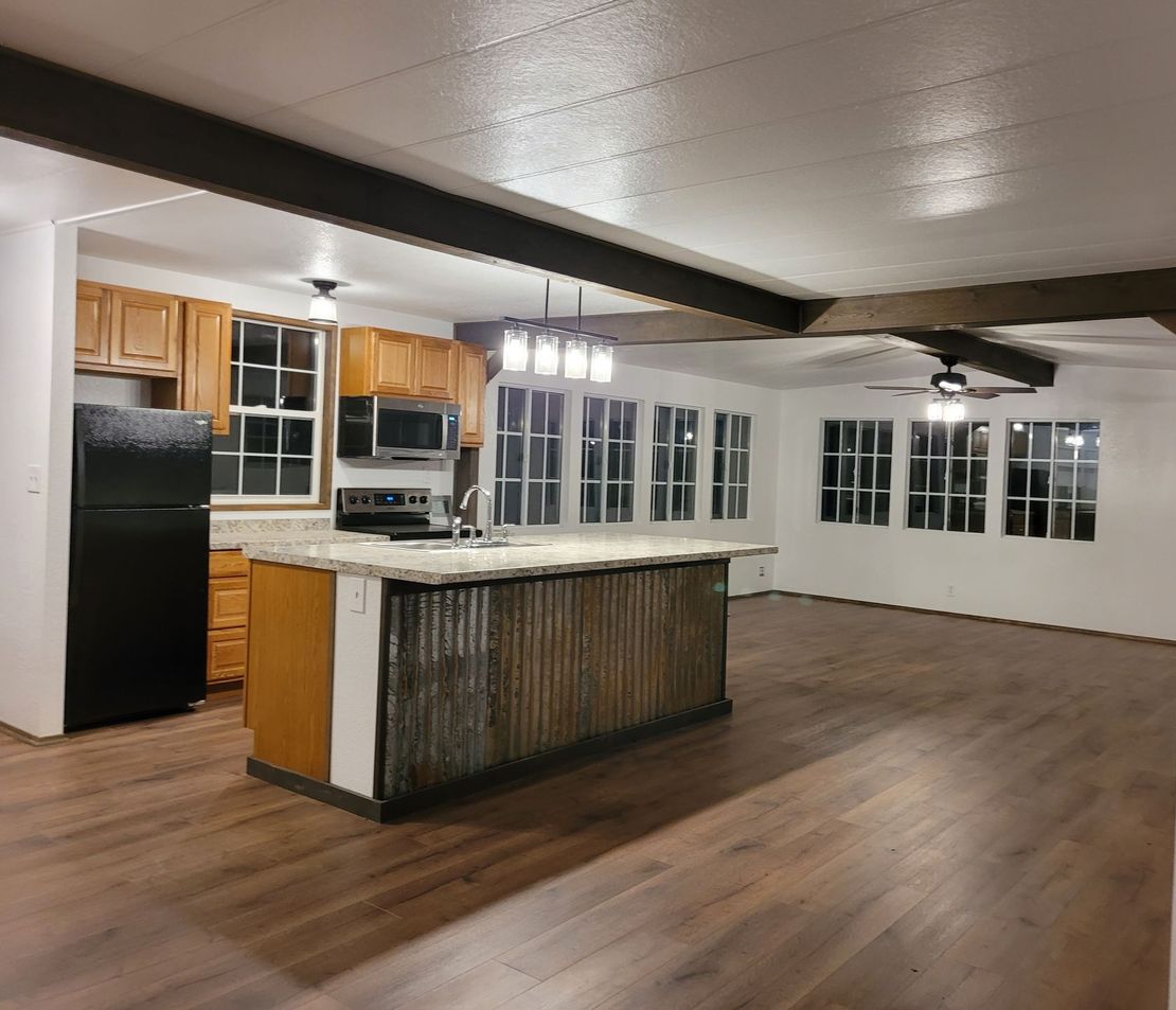A kitchen with a large island and a black refrigerator