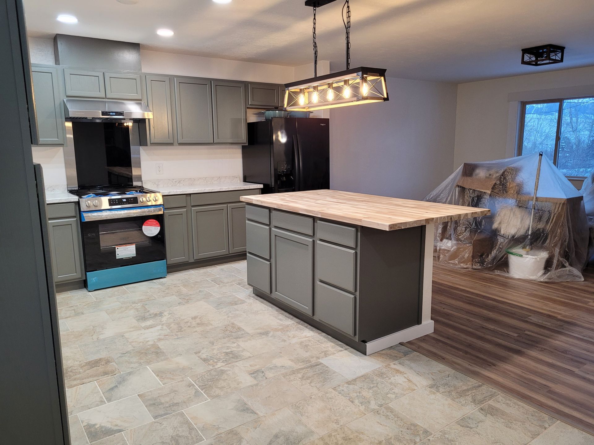 Newly renovated kitchen with gray cabinets, a center island, and new appliances. The space has new flooring.