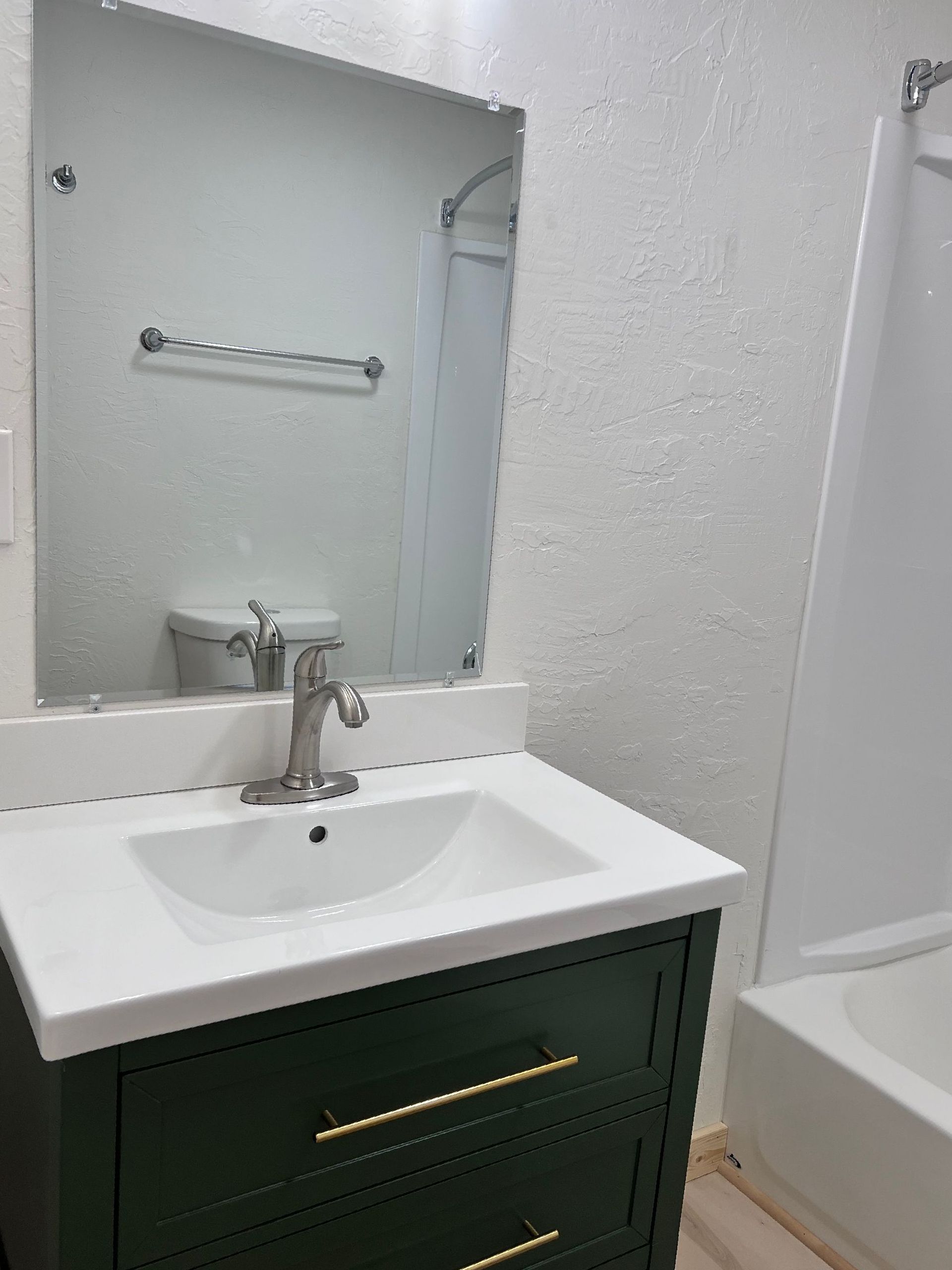 A bathroom with a sink , mirror and tub.