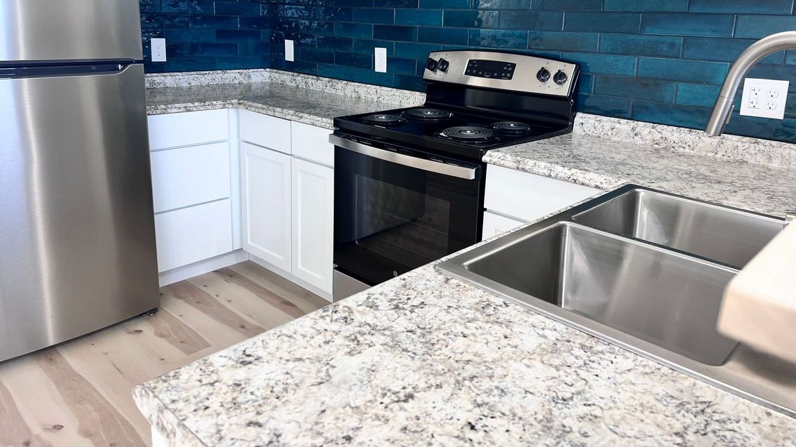 A kitchen with a stove , refrigerator , sink and microwave.