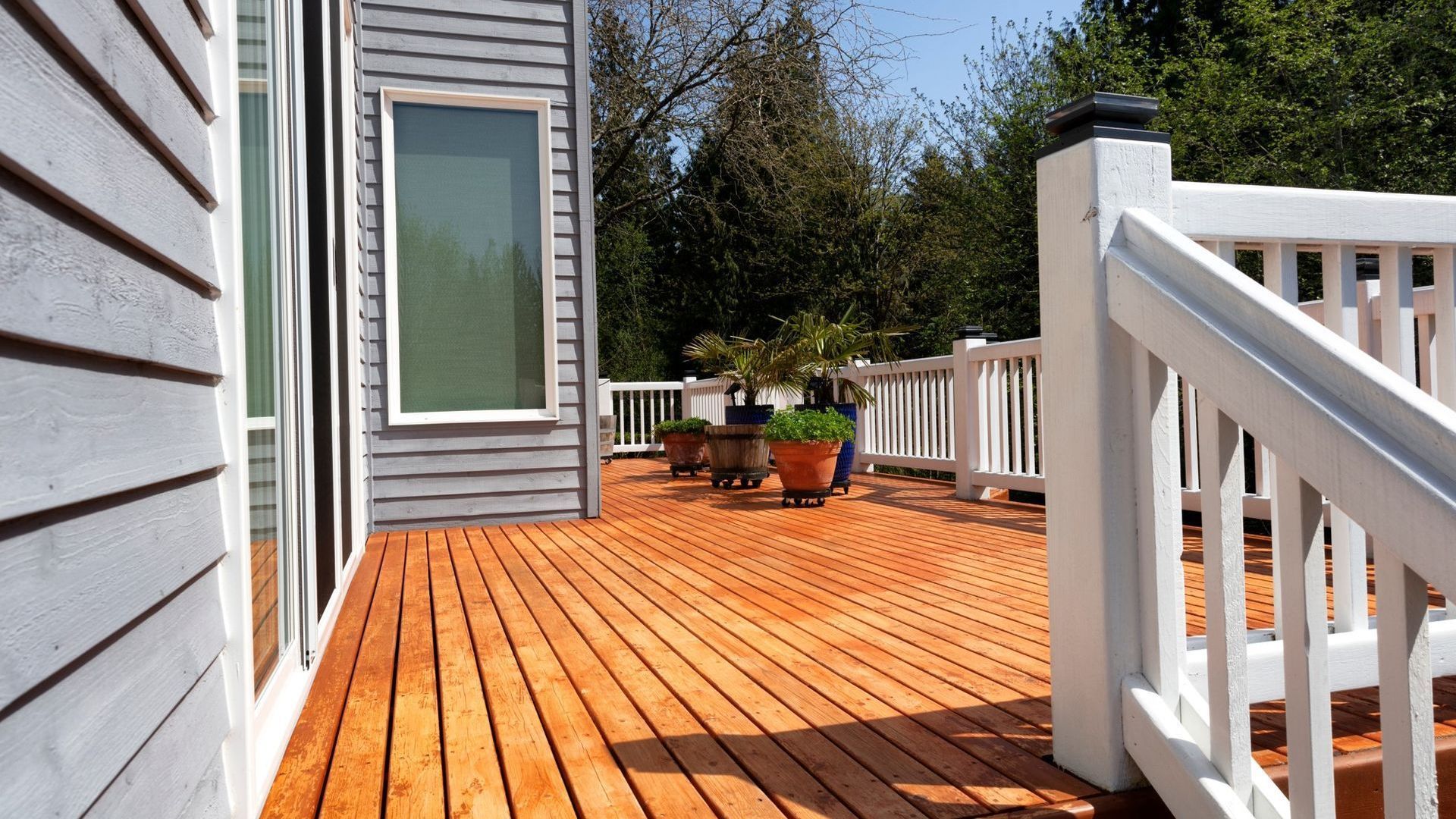 A wooden deck with a white railing in front of a house
