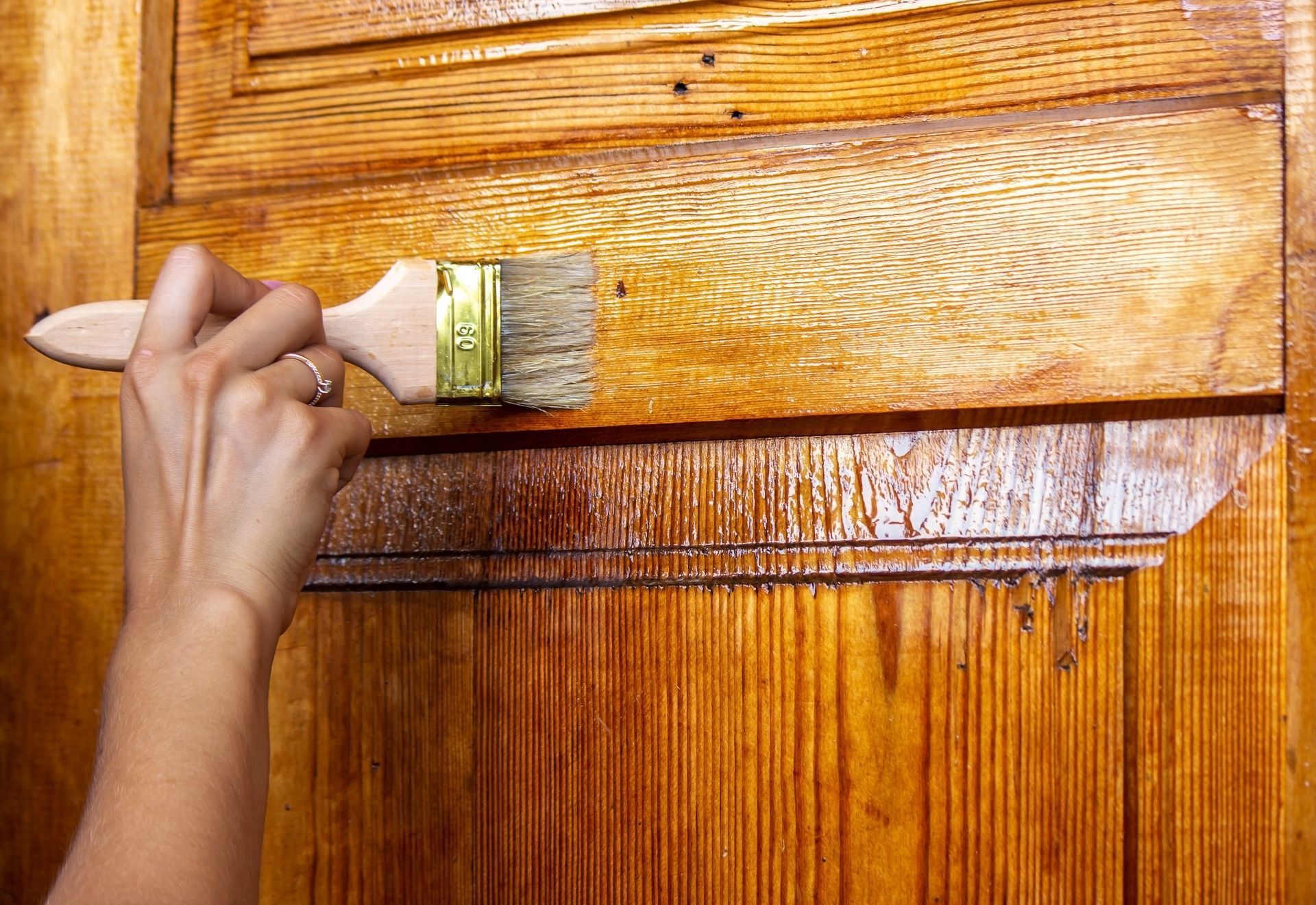 A person is painting a wooden door with a brush.