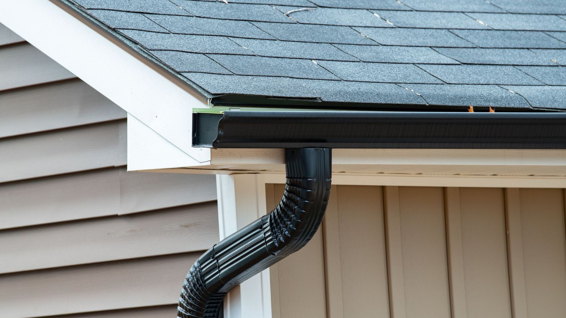 A close up of a gutter on the side of a house.
