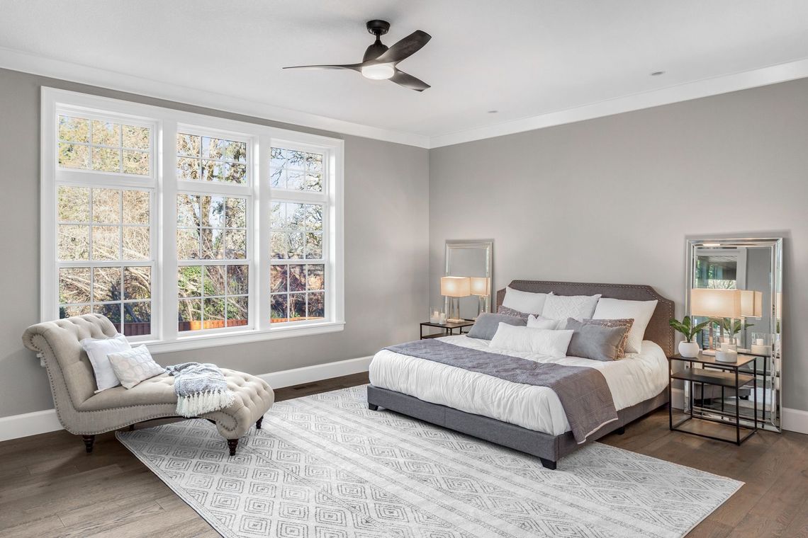 A bedroom with a bed , chair , and ceiling fan.