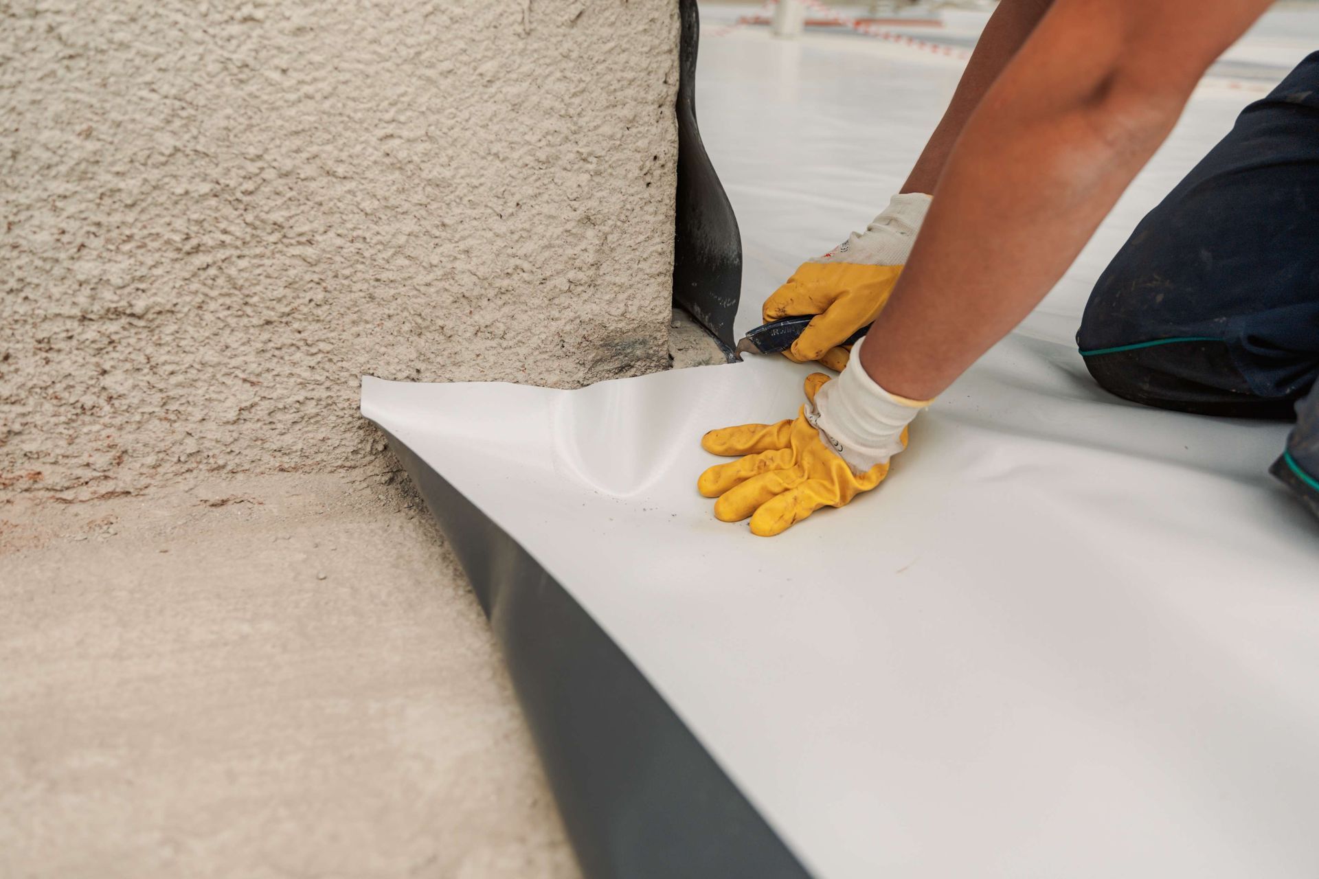 A person is cutting a piece of plastic on the ground.