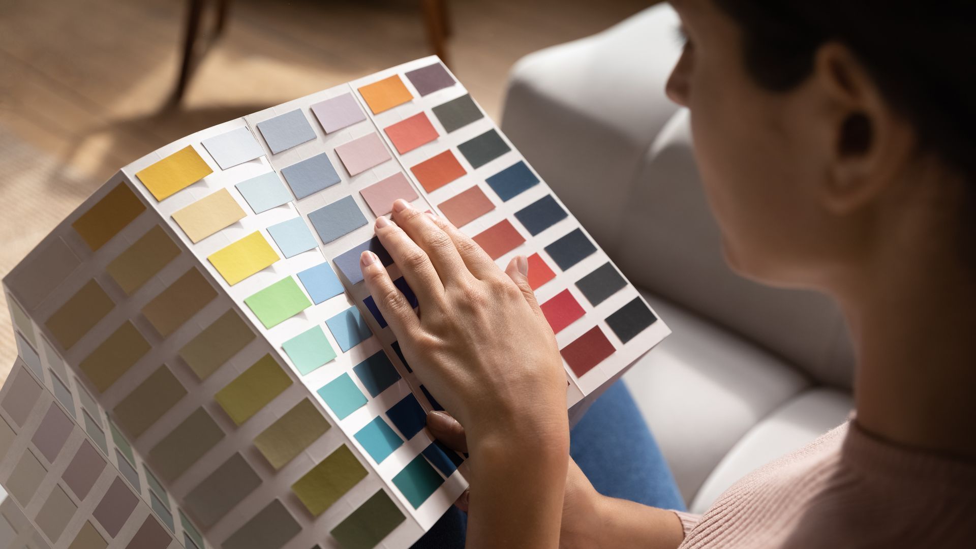 A woman is sitting on a couch looking at a color palette.