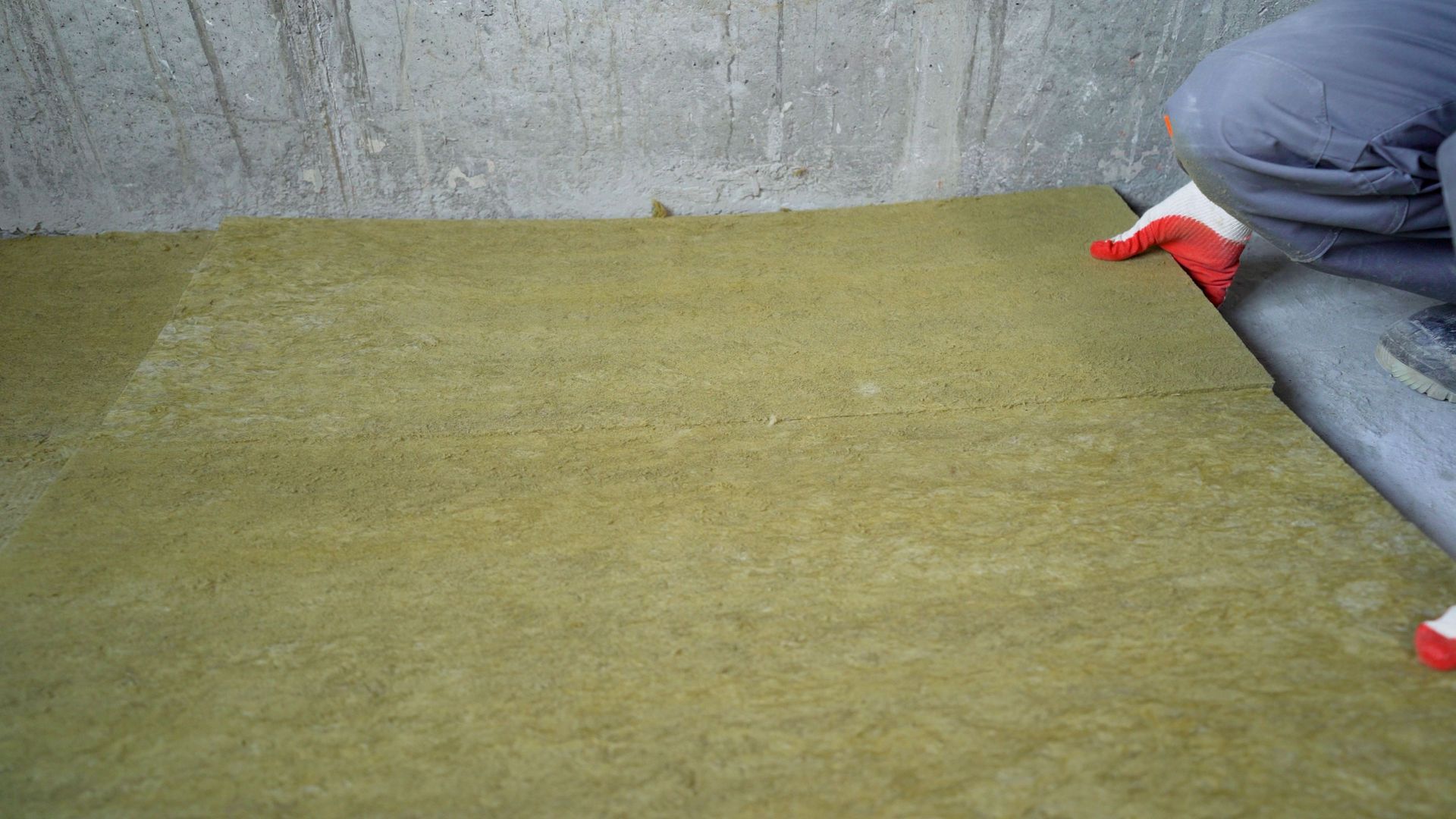 A person is laying a sondproofing material on the floor.