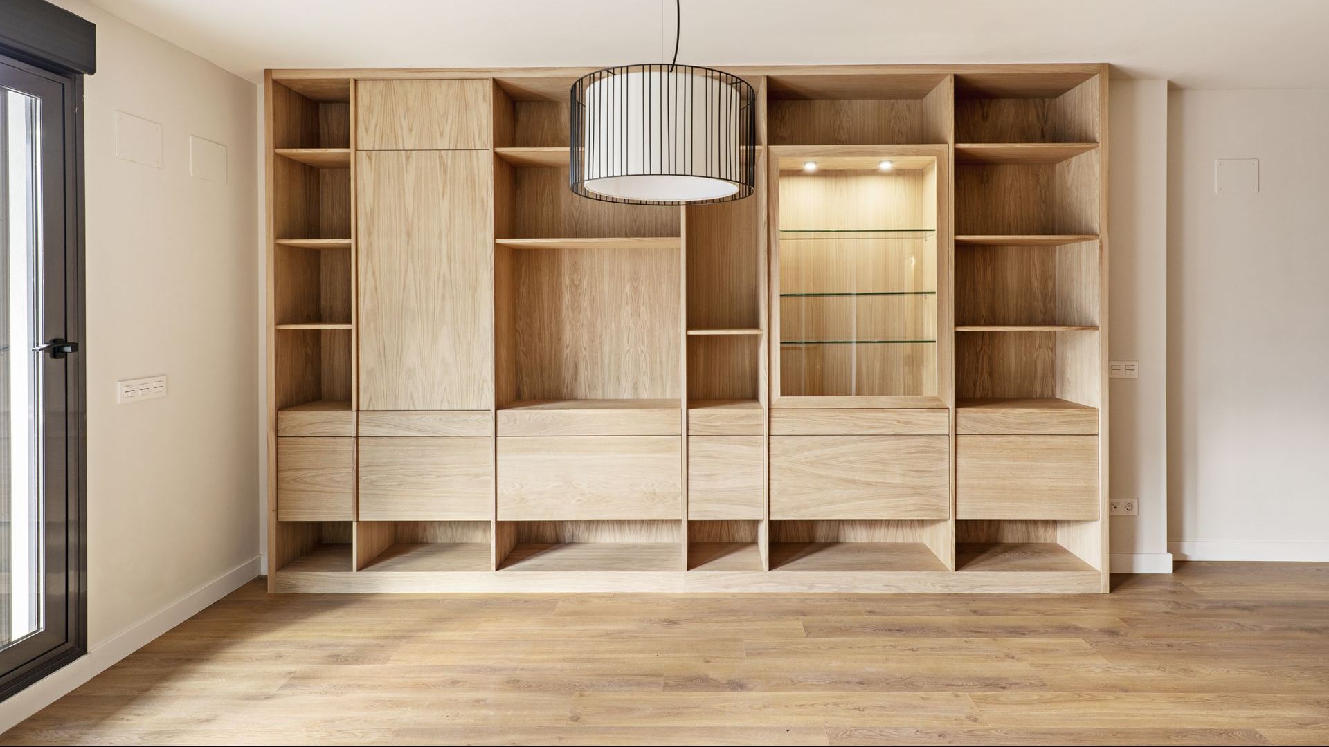 An empty room with a lot of wooden shelves and drawers.