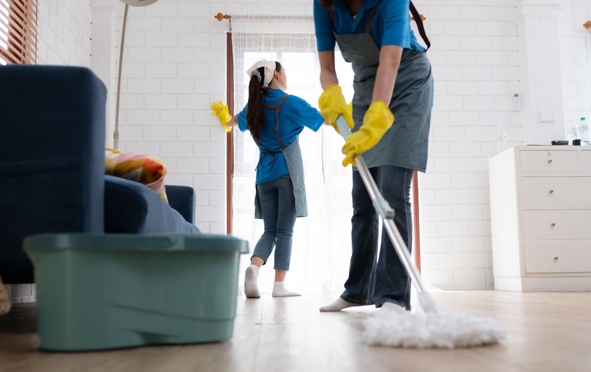 A woman and a little girl are cleaning the floor in a living room.