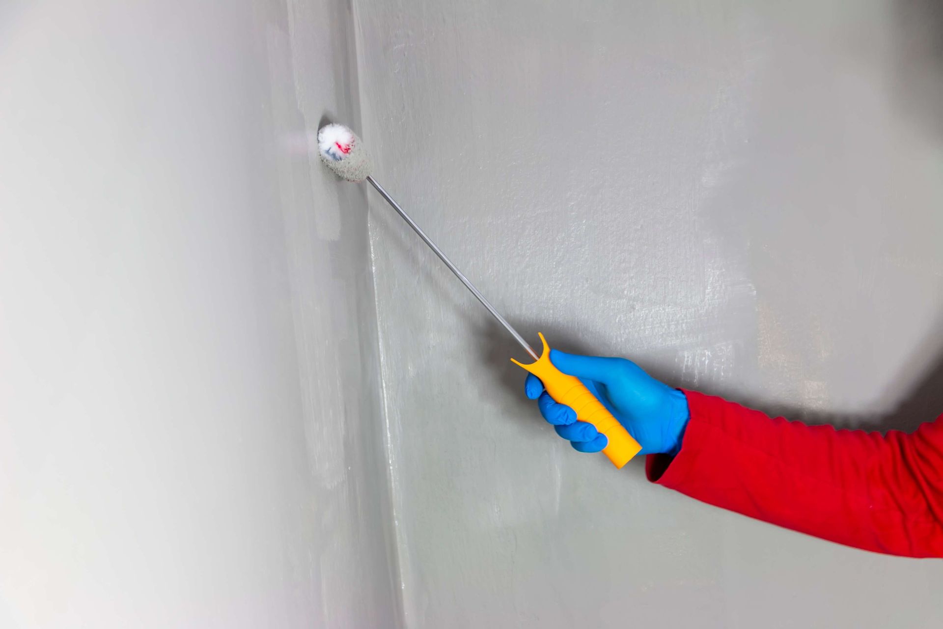 A person is waterprofing bathroom wall.
